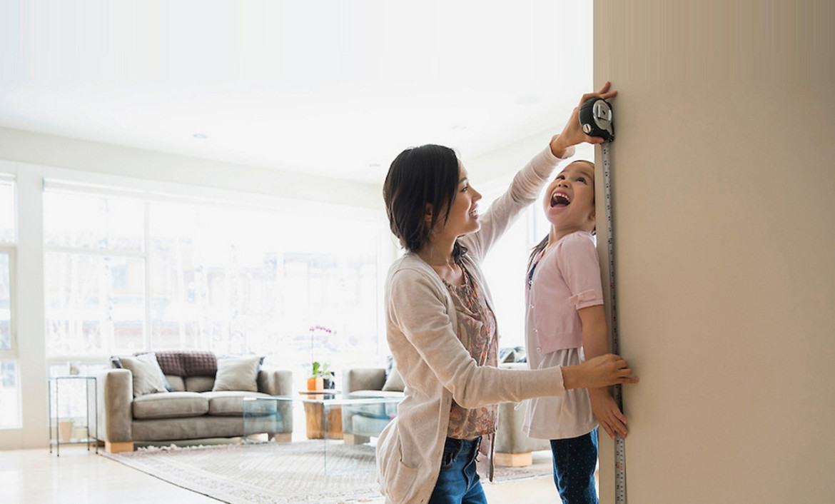 Mother measures child's height and marks door frame.